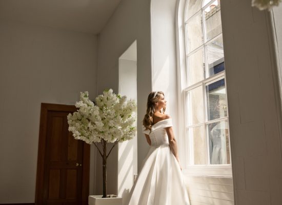 6S2A2889 Patrick bride looking out arched window with sun shining on her