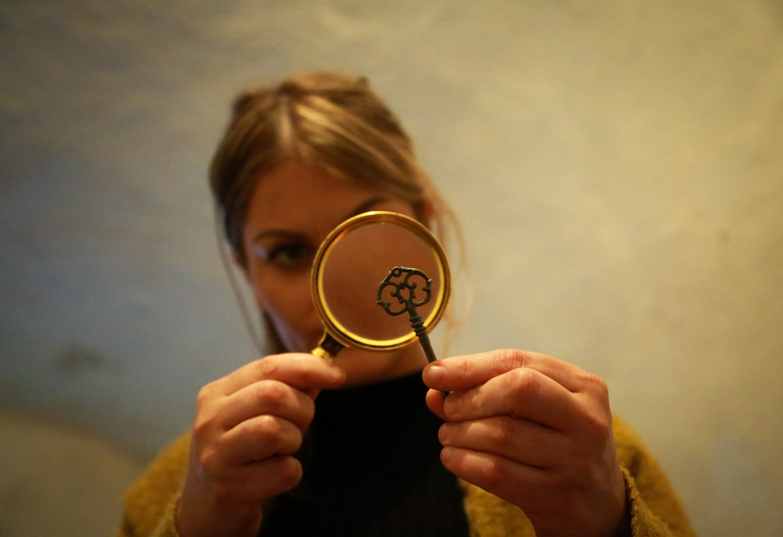 woman looking at key through magnifying glass