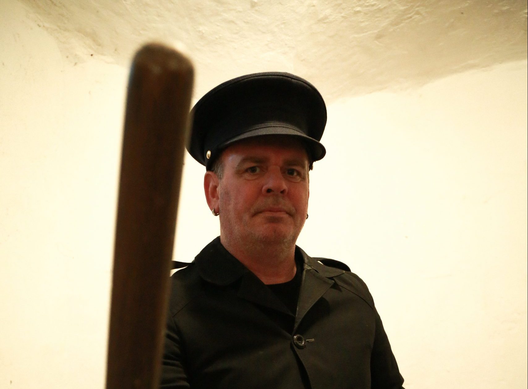 prison guard with batton leaning towards camera